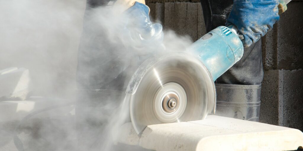 Worker cutting stone with grinder.