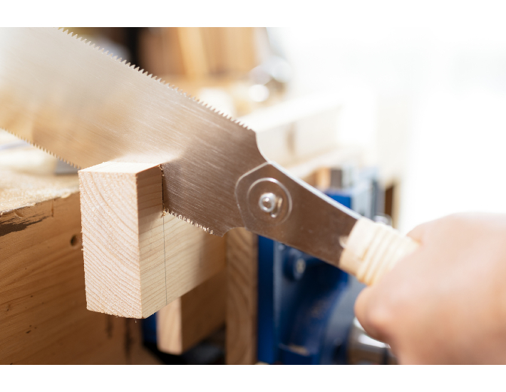 A Japanese saw being used to cut through a block of wood.