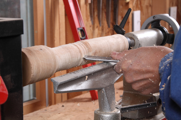 A man sharpening a metal object on a lathe, demonstrating the precision and care needed to achieve the best lathe tools results.